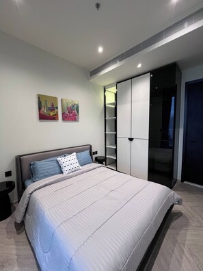 Un dormitorio con cama, mesitas de noche, un armario y dos cuadros colgados en la pared.