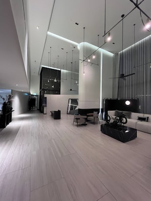 A modern interior with a high ceiling, pendant lighting, a sofa set, and a coffee table. - Panoramic River View Condo, Long Stay (Bangkok)