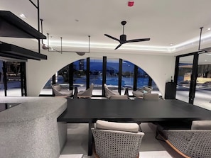 Un comedor moderno con una mesa grande, sillas y vistas a una piscina.