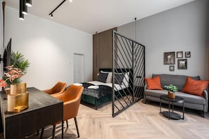 Een moderne kamer met een bed, een slaapbank, een eettafel en een televisie.