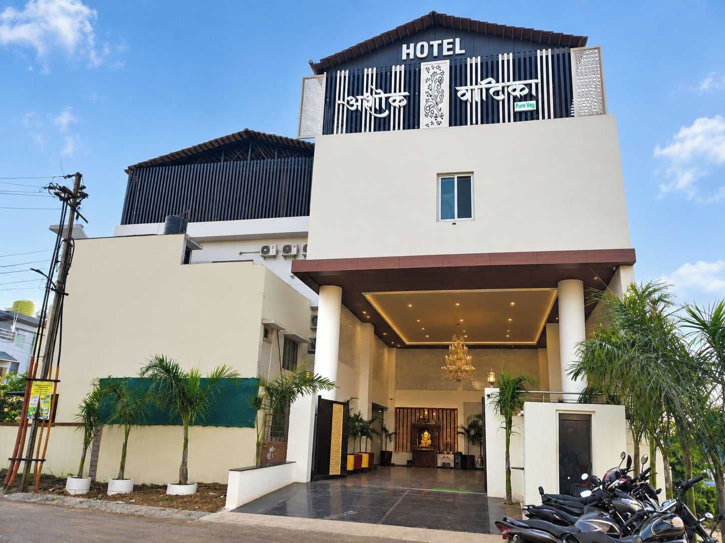 Un hotel con fachada moderna, un acceso cubierto y un estacionamiento con motocicletas.