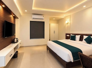A modern hotel room with a bed, a TV, an air conditioning unit, and a wardrobe.