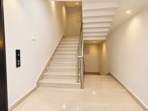 A modern staircase with a metal handrail, a digital floor indicator, and a clean, minimalist design. - Palette Khadgaon Road Lavha (Nagpur)