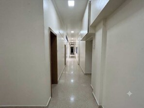 A long, narrow hallway with doors on both sides, leading to rooms. - Palette Khadgaon Road Lavha (Nagpur)