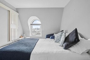 Ein Schlafzimmer mit einem großen Bett, einem Fenster mit Rundbogen und Blick ins Freie.