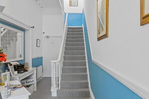 Eine Treppe mit weißer Geländer und Streifenmuster Teppich, die zu einer Tür führt.