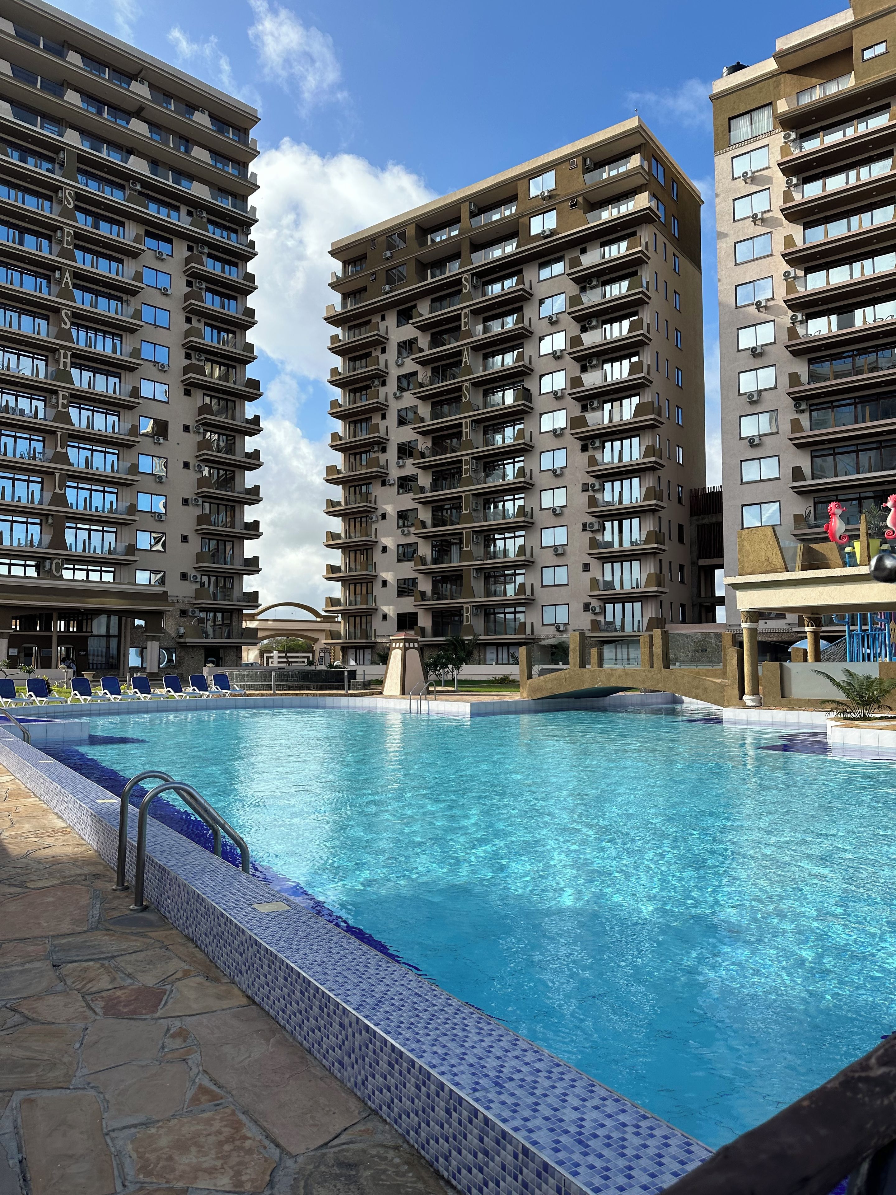 A swimming pool with a tiled edge, surrounded by high-rise residential buildings.