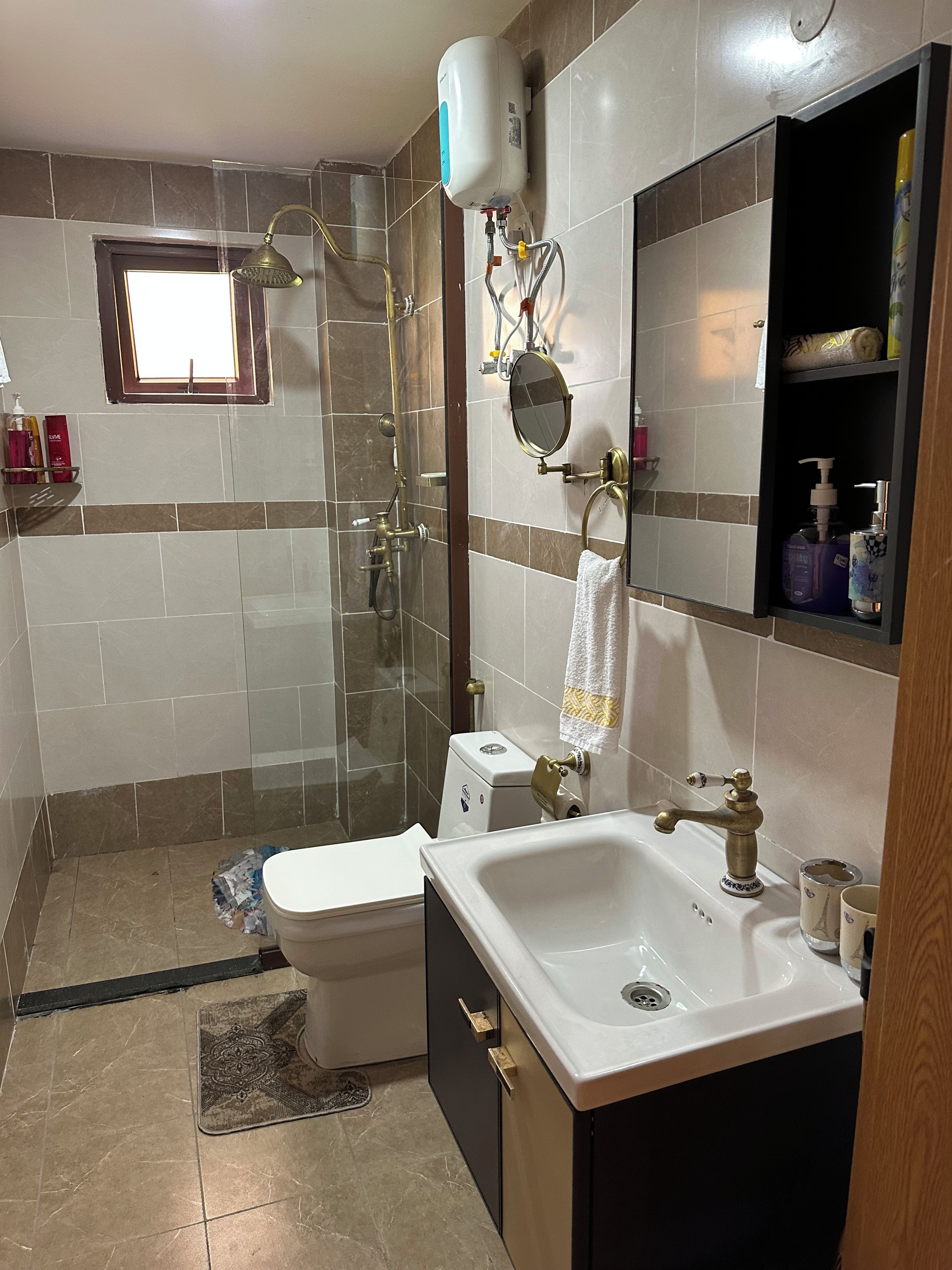 A bathroom with a toilet, sink, shower, and a mirror.