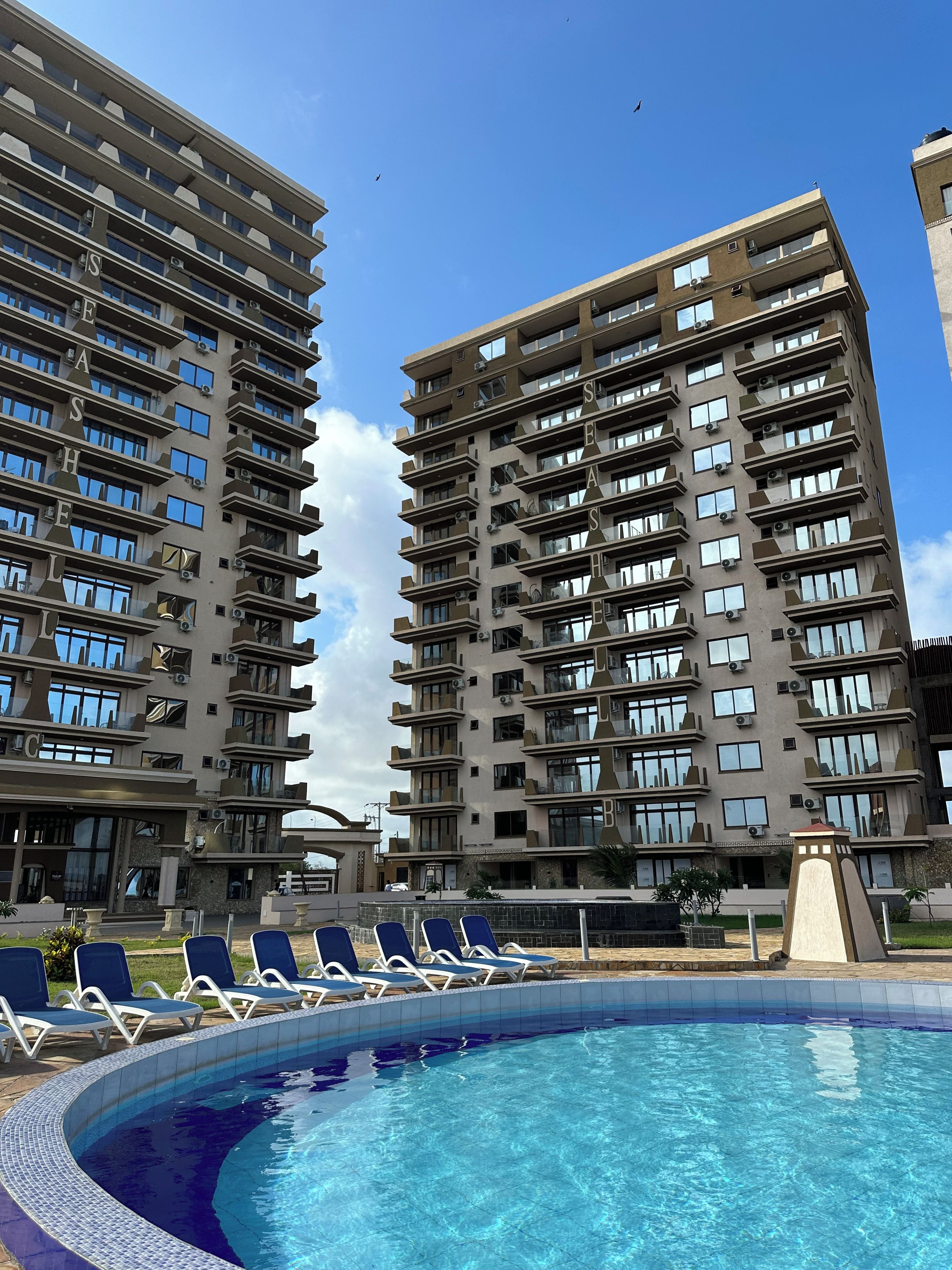 Un moderno edificio de apartamentos con piscina y sillones de descanso.