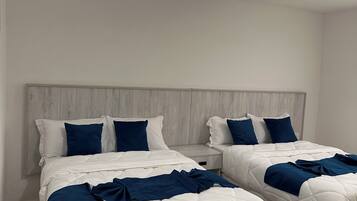 A hotel room with two beds, a wooden headboard, and a hanging light fixture.