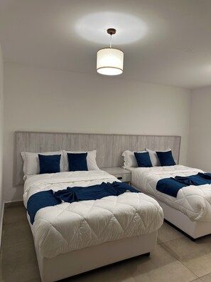 Ein Hotelzimmer mit zwei Betten, einem Holzkopfteil und einer Hängelampe.