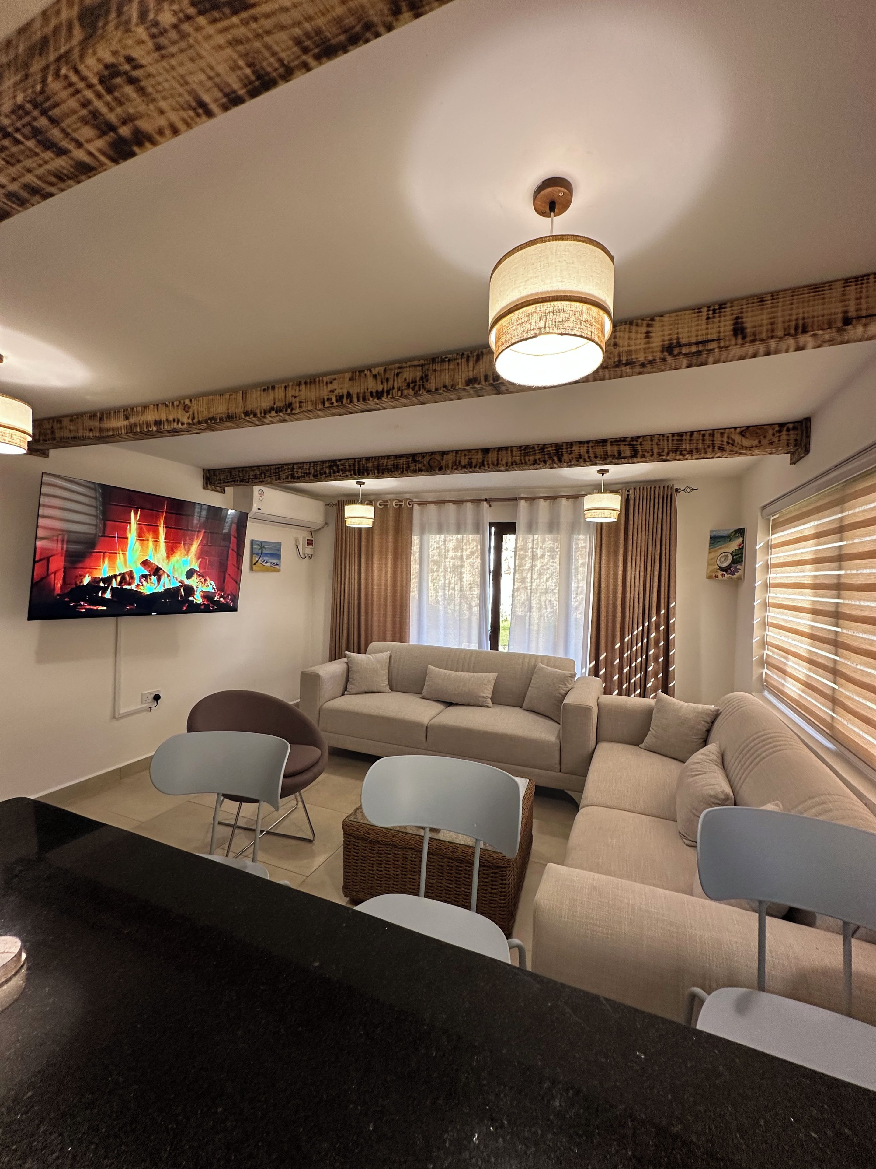 Una sala de estar con un sofá, sillas, un televisor y una chimenea.