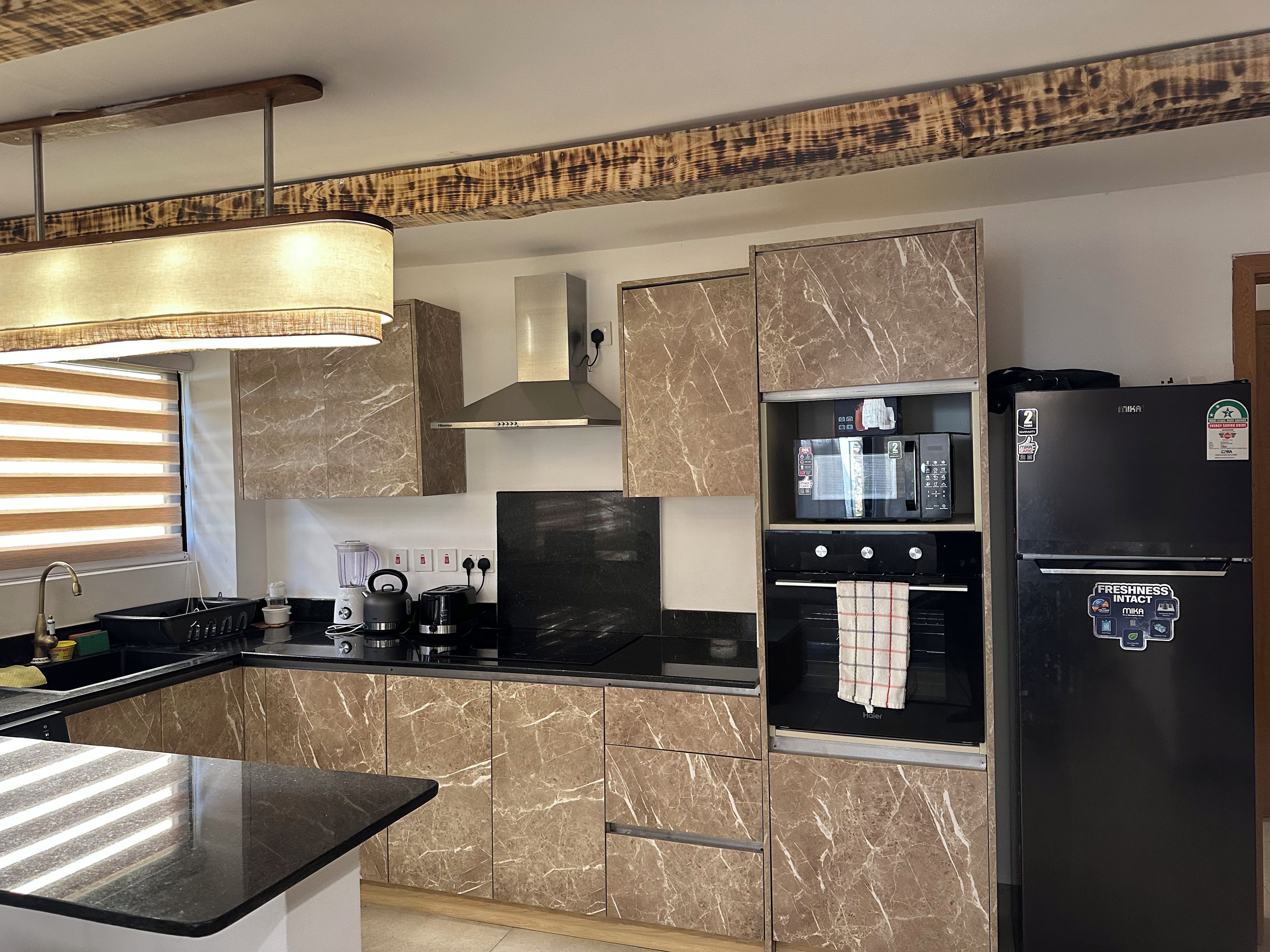 Una cocina moderna con armarios de mármol, un refrigerador negro y un horno empotrado.