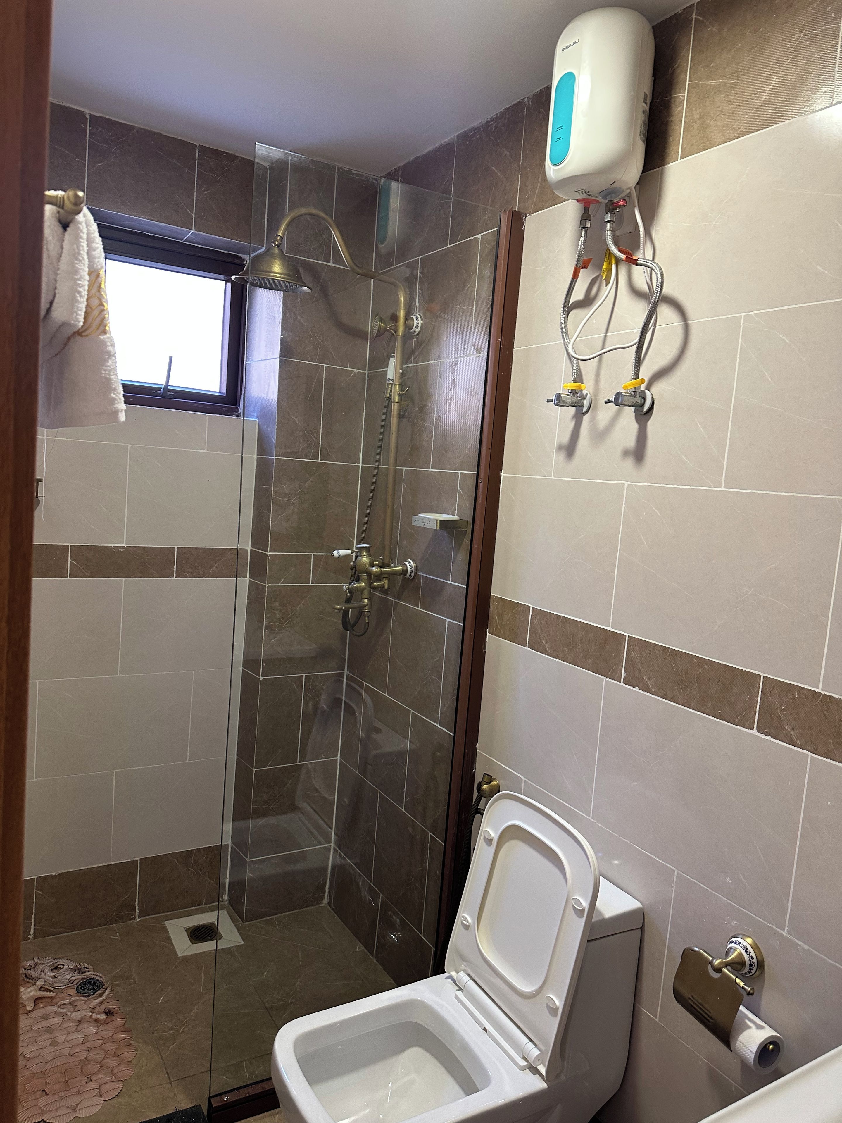 A bathroom with a shower, toilet, and a towel rack.