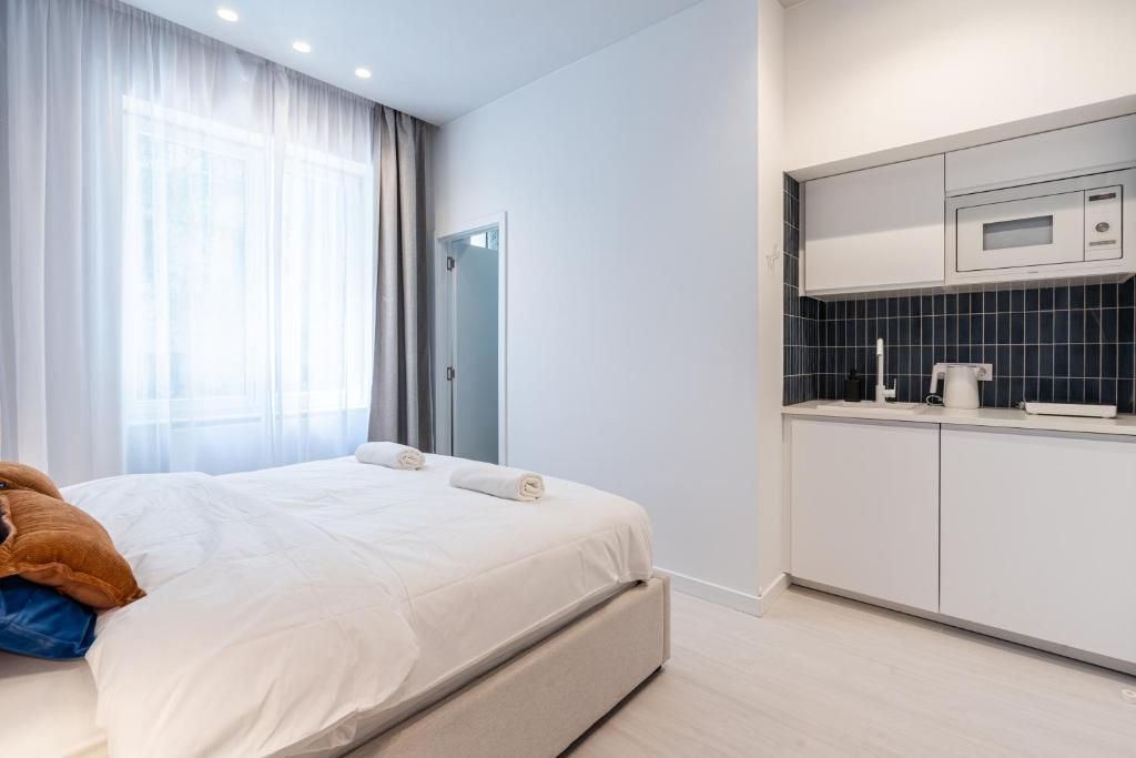 Ein modernes Hotelzimmer mit einem Bett, einer Küchenzeile und einer Badezimmertür.