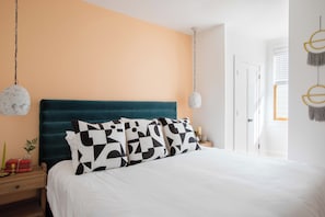 A bedroom with a teal headboard, white bedding, and geometric patterned pillows. - The Silver Spring - Prime Downtown Location (Charleston)