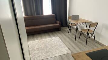 Un espacio habitable moderno con un sofá, una mesa de comedor con sillas y un ordenador portátil sobre la mesa.