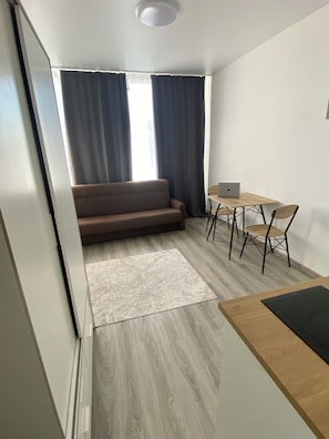 A modern living space with a sofa, a dining table with chairs, and a laptop on the table.