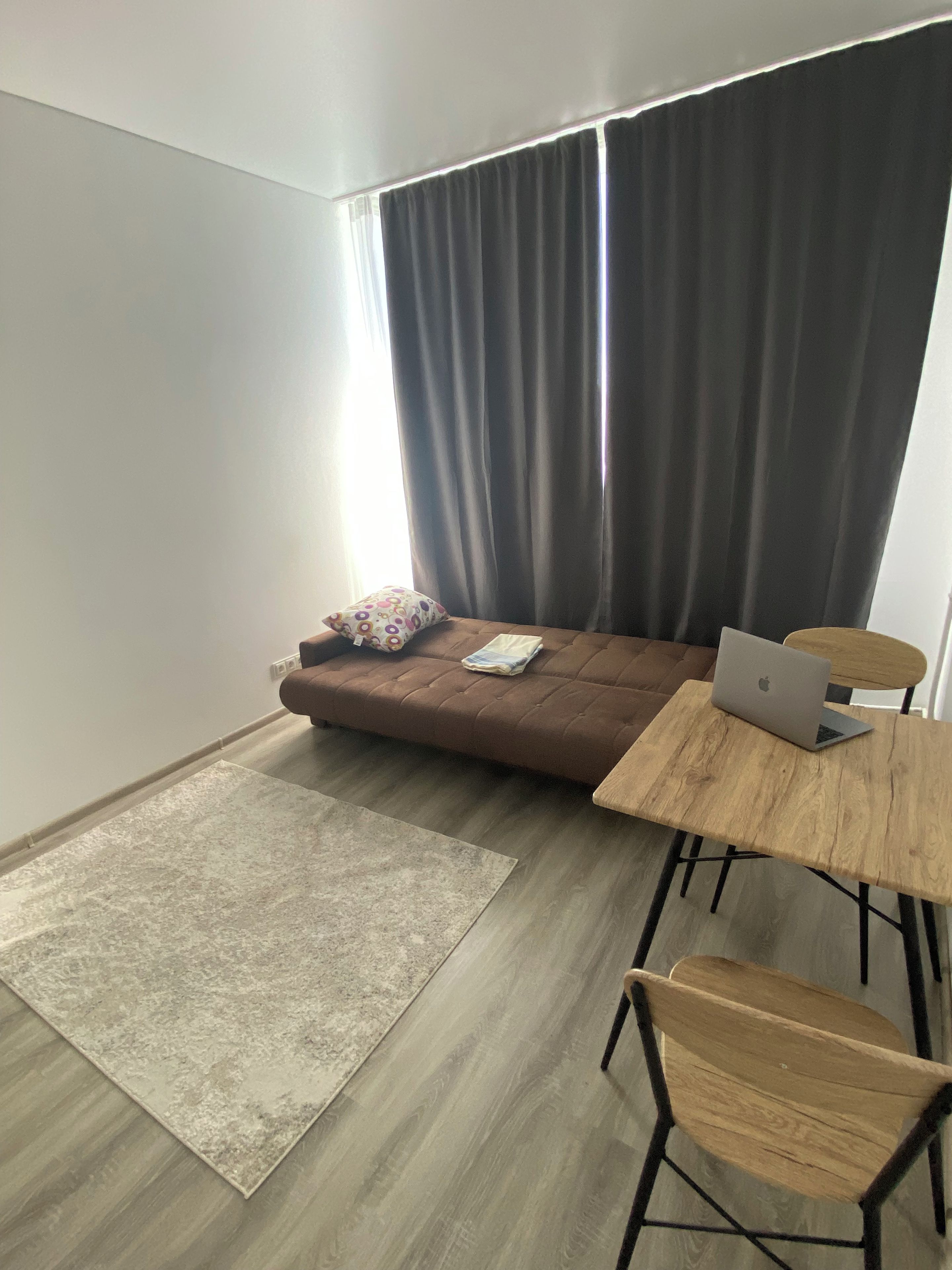 Een moderne woonruimte met een bruine bank, een houten tafel en een laptop.