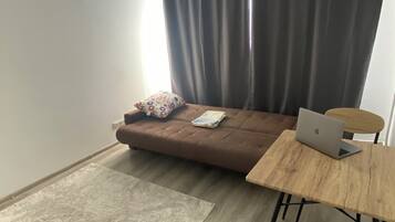 Een moderne woonruimte met een bruine bank, een houten tafel en een laptop.