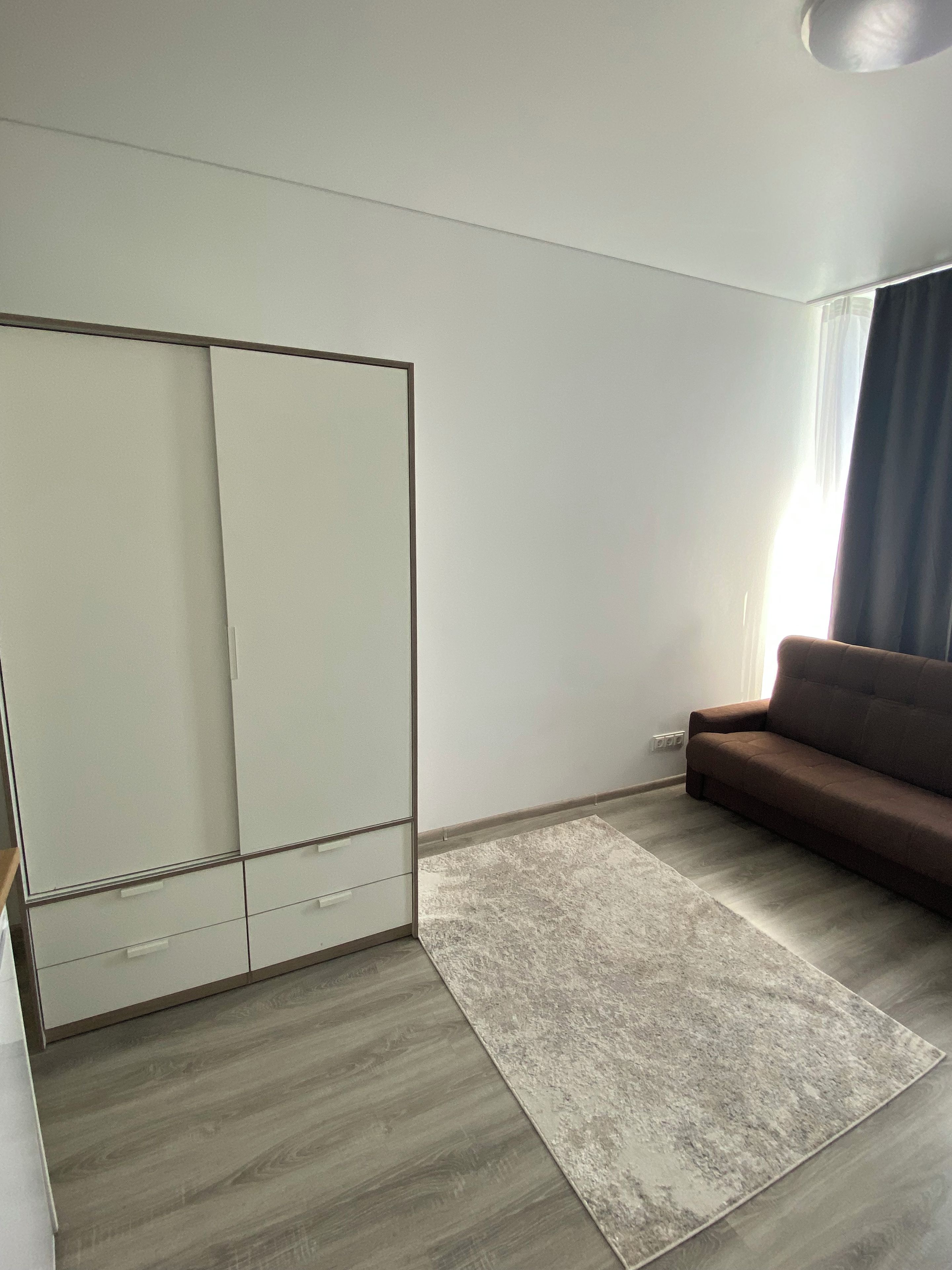 A room with a wardrobe, a sofa, and a rug.