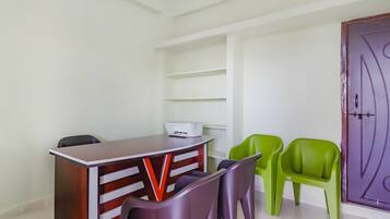 A room with a wooden desk, two chairs, a printer, and a purple door.