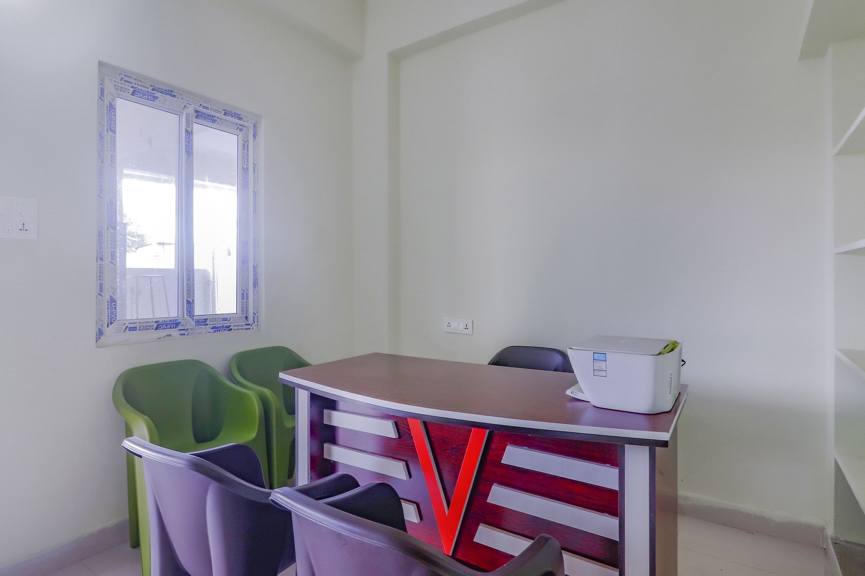 Una habitación con una mesa, sillas, un ventanal e impresora.
