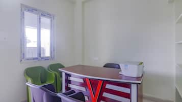 Una habitación con una mesa, sillas, un ventanal e impresora.