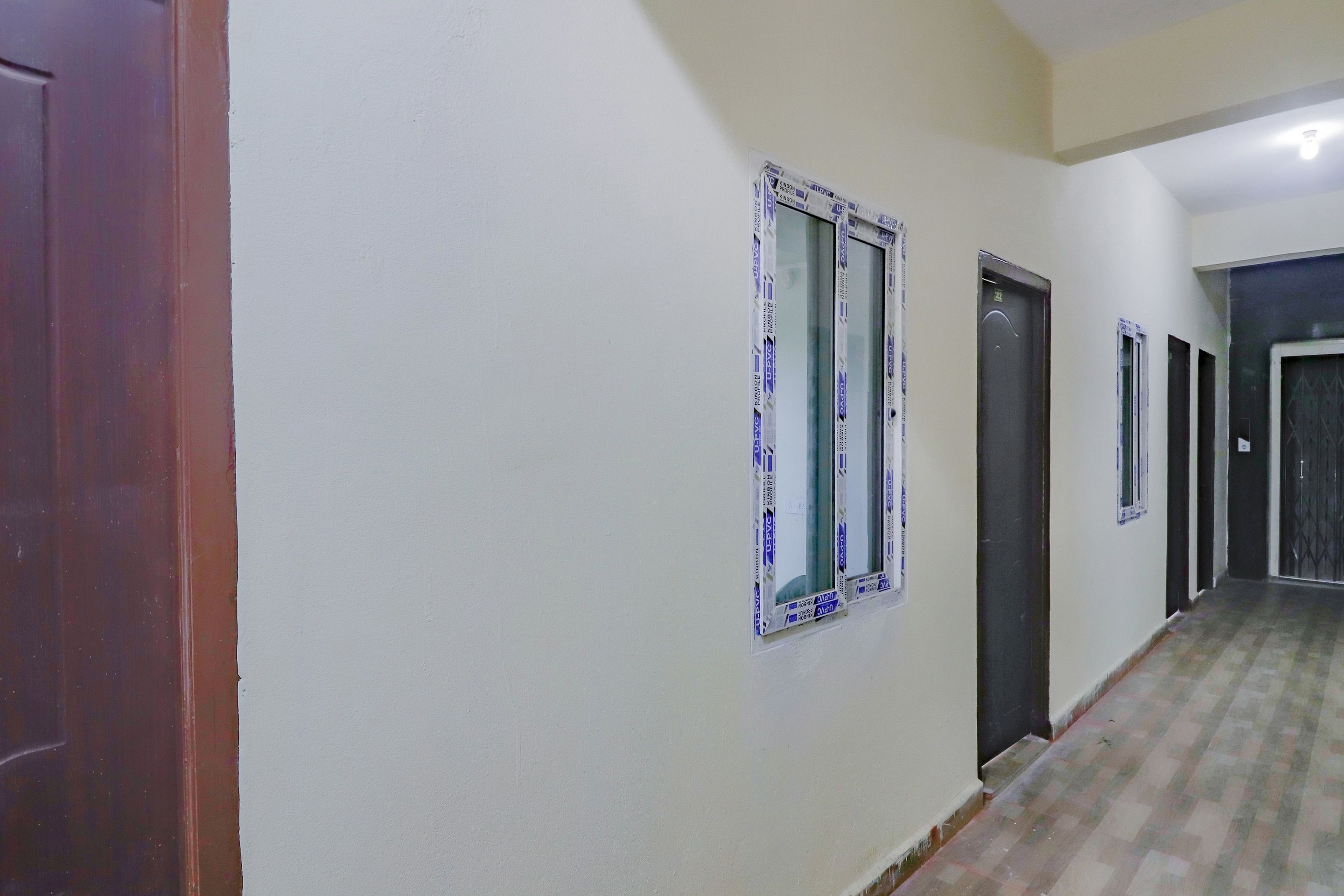 Un pasillo con puertas y ventanas, algunas cubiertas con plástico protector.