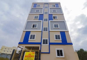 Een meerhoog gebouw met een bordje dat 'SRI RESIDENCY' vermeldt, wat luxe kamers aangeeft.
