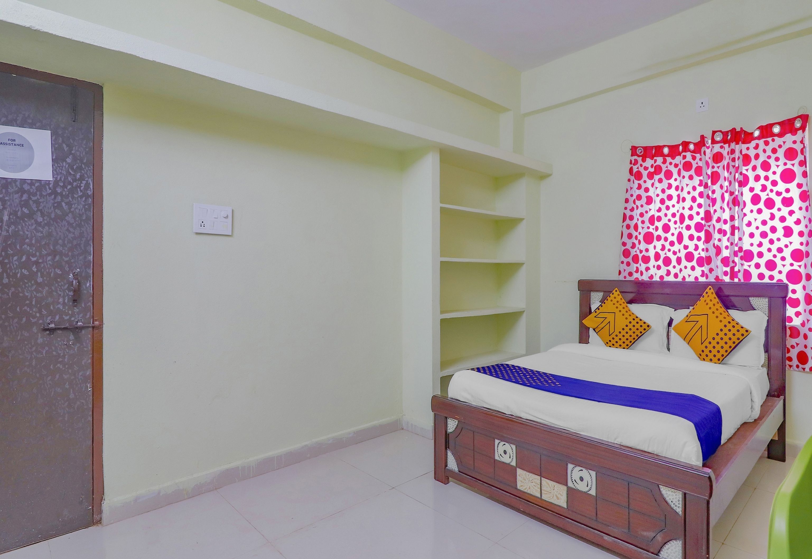Un dormitorio con una cama de madera, una estantería, una puerta y una cortina con estampado de lunares.