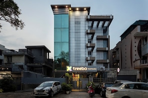 A modern building with a sign for 'treebo Parth Paradise' and a parking area with cars. - Treebo Parth Paradise (Ghaziabad)
