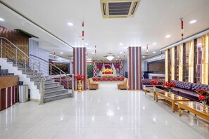 A spacious lobby with a grand staircase, a stage with floral decorations, and seating arrangements. - Treebo Parth Paradise (Ghaziabad)