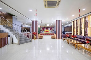 A spacious lobby with a grand staircase, a stage with floral decorations, and seating arrangements. - Treebo Parth Paradise (Ghaziabad)