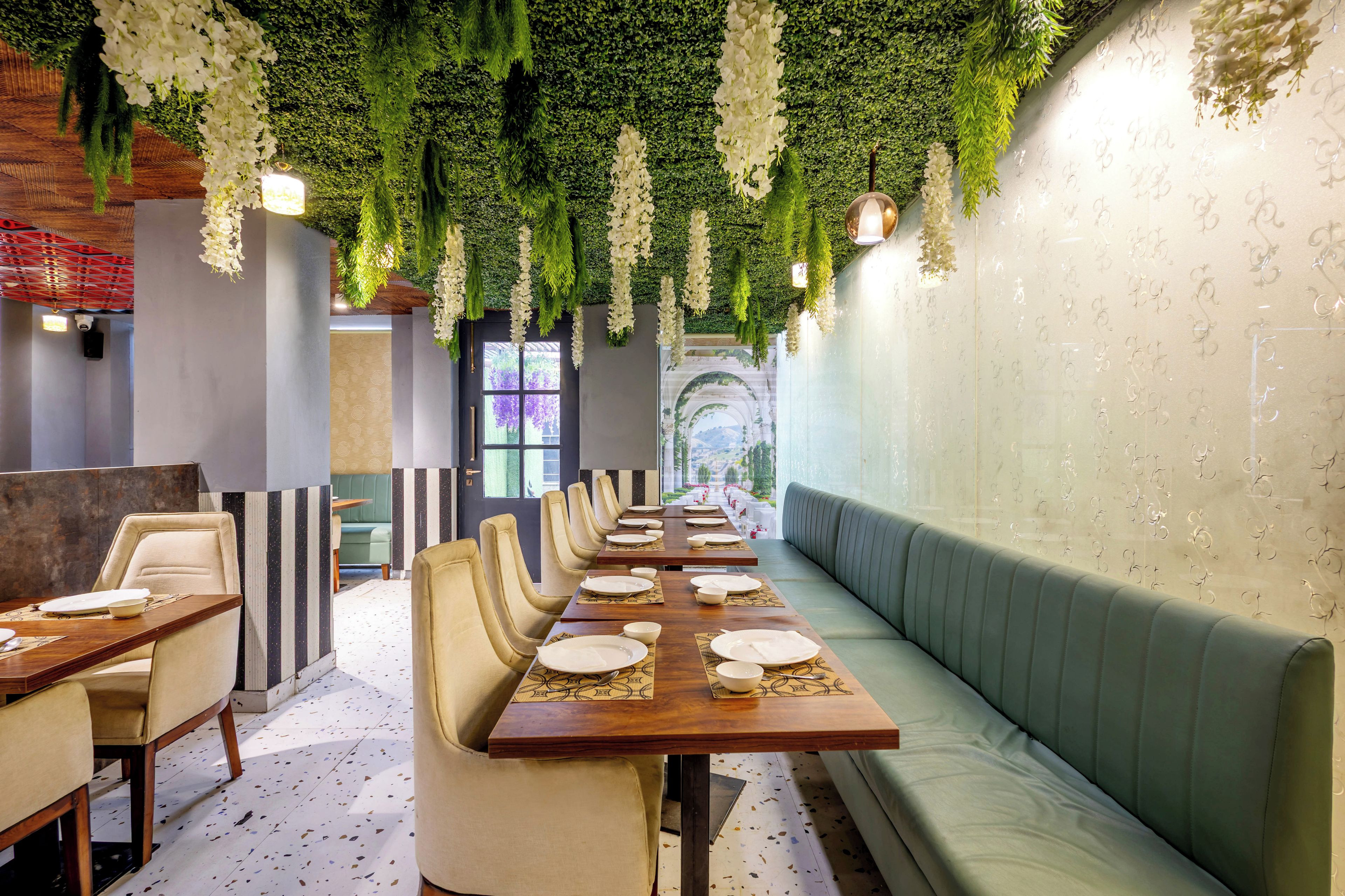Un restaurant doté d’une longue table à manger, de sièges confortables et d’un mur végétal.