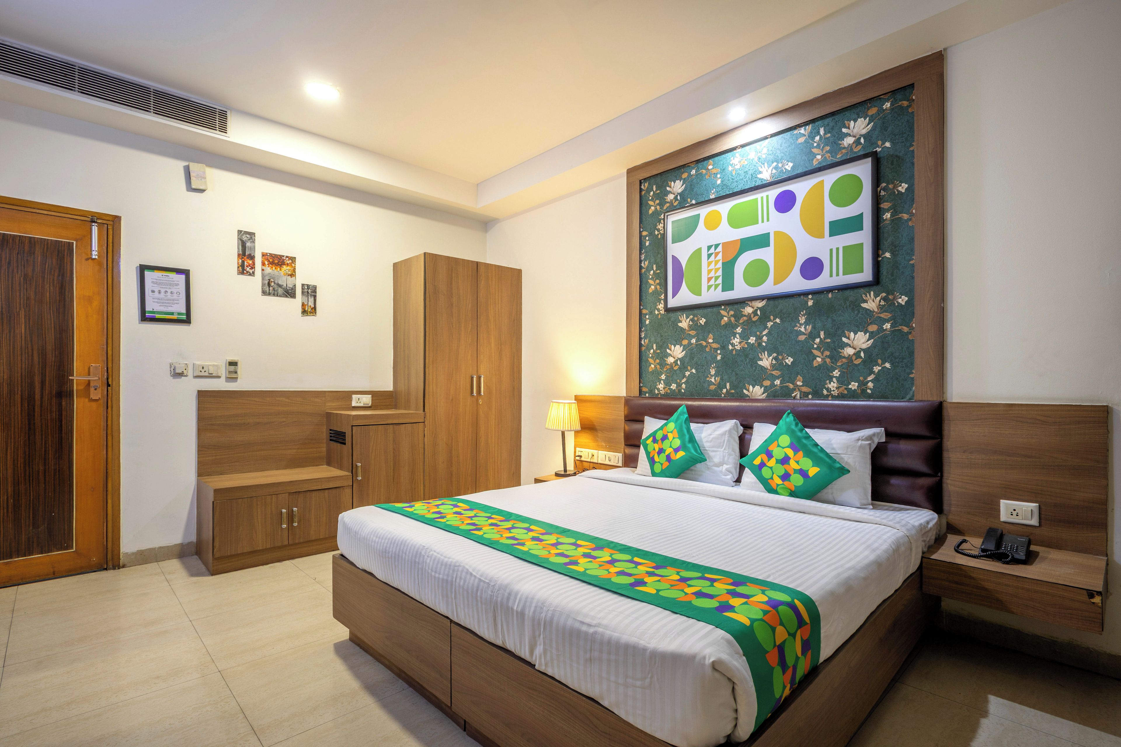 Une chambre d’hôtel avec un grand lit, une armoire en bois et une œuvre d’art accrochée au mur.