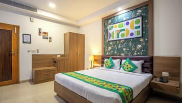 A hotel room with a large bed, wooden wardrobe, and a wall-mounted artwork.
