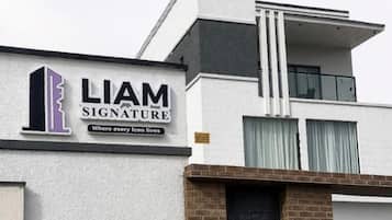 Un edificio moderno con un cartel que dice 'LIAM SIGNATURE' y un eslogan que reza 'Donde vive cada icono'.