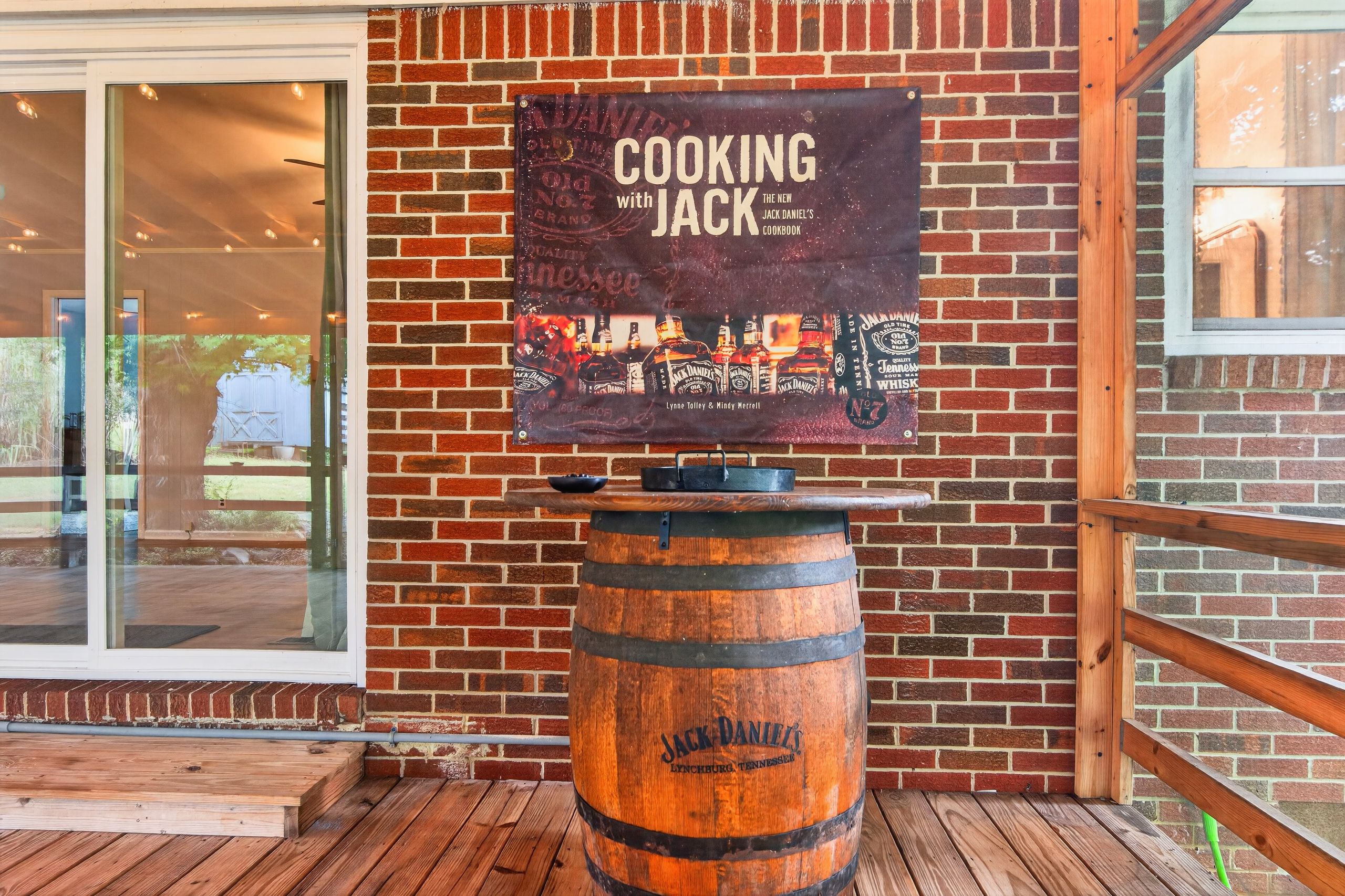 A brick wall with a sign for 'Cooking with Jack Daniel's' and a wooden barrel.