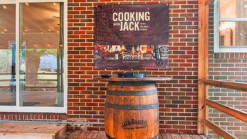 A brick wall with a sign for 'Cooking with Jack Daniel's' and a wooden barrel.