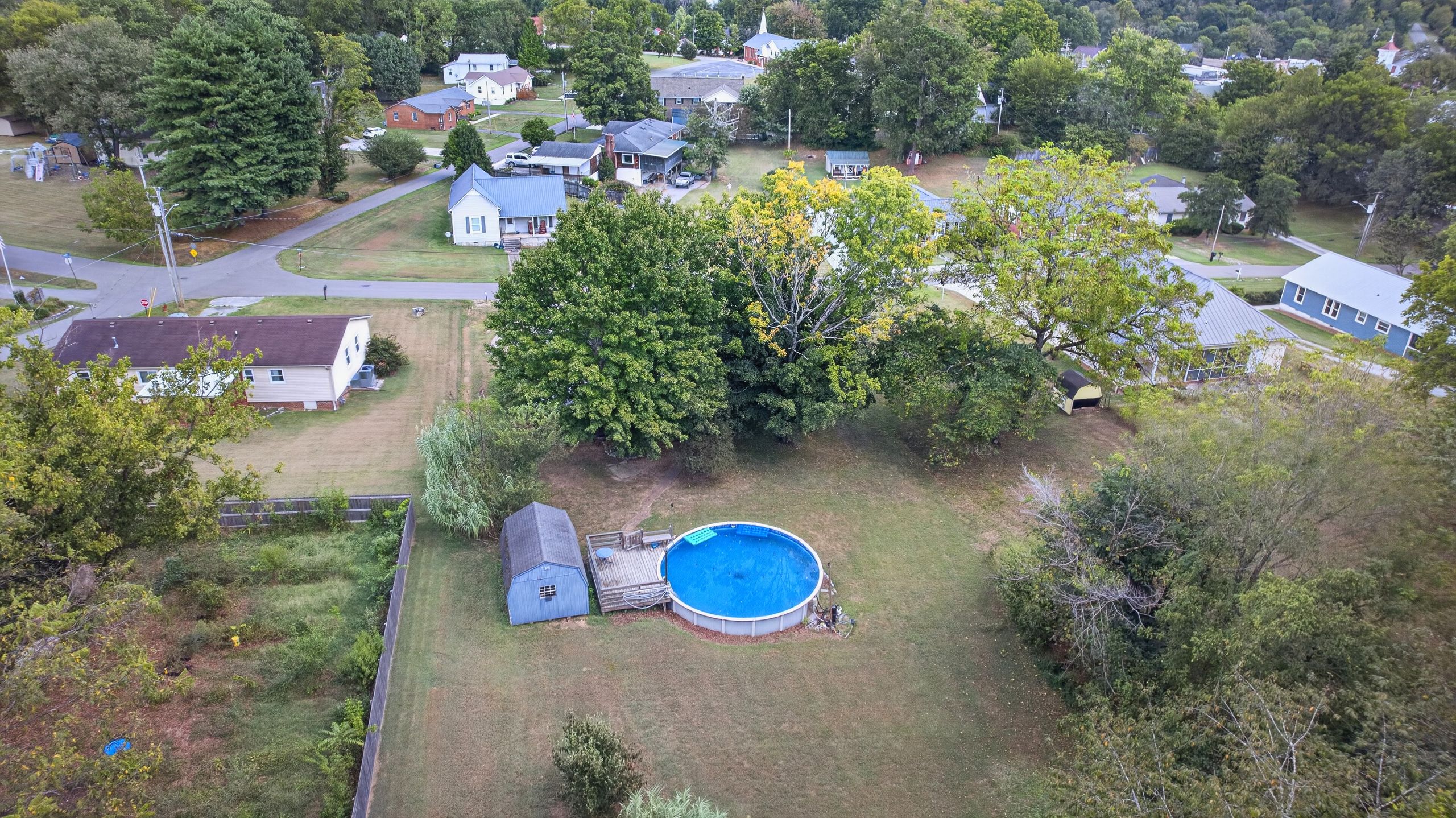 Un barrio residencial con piscina, patio cercado y casas.