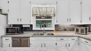 A modern kitchen with white cabinets, a stainless steel sink, a microwave, and a toaster.