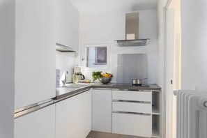 A compact kitchen with white cabinetry, a built-in oven, a coffee maker, and a window above the sink. - Attico con vista (Firenze)