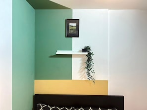 A room with a green and white wall, a black headboard, a white shelf with a plant, and a framed picture. - Double Bed Partition Room in Al Barsha1 (Dubai)