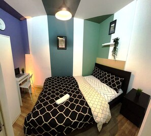 Een slaapkamer met een bed, een bureau en een stoel.