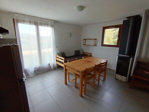 Cocina compacta con mesa, sillas, sofá y refrigerador.