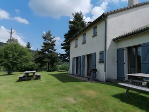 Un edificio con fachada blanca, amplias ventanas y un patio con césped y una mesa de picnic.