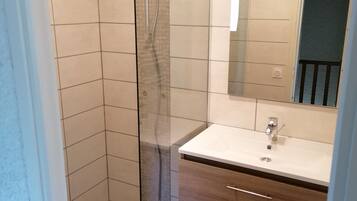 A modern bathroom with a glass-enclosed shower, a white sink, and a wooden vanity.