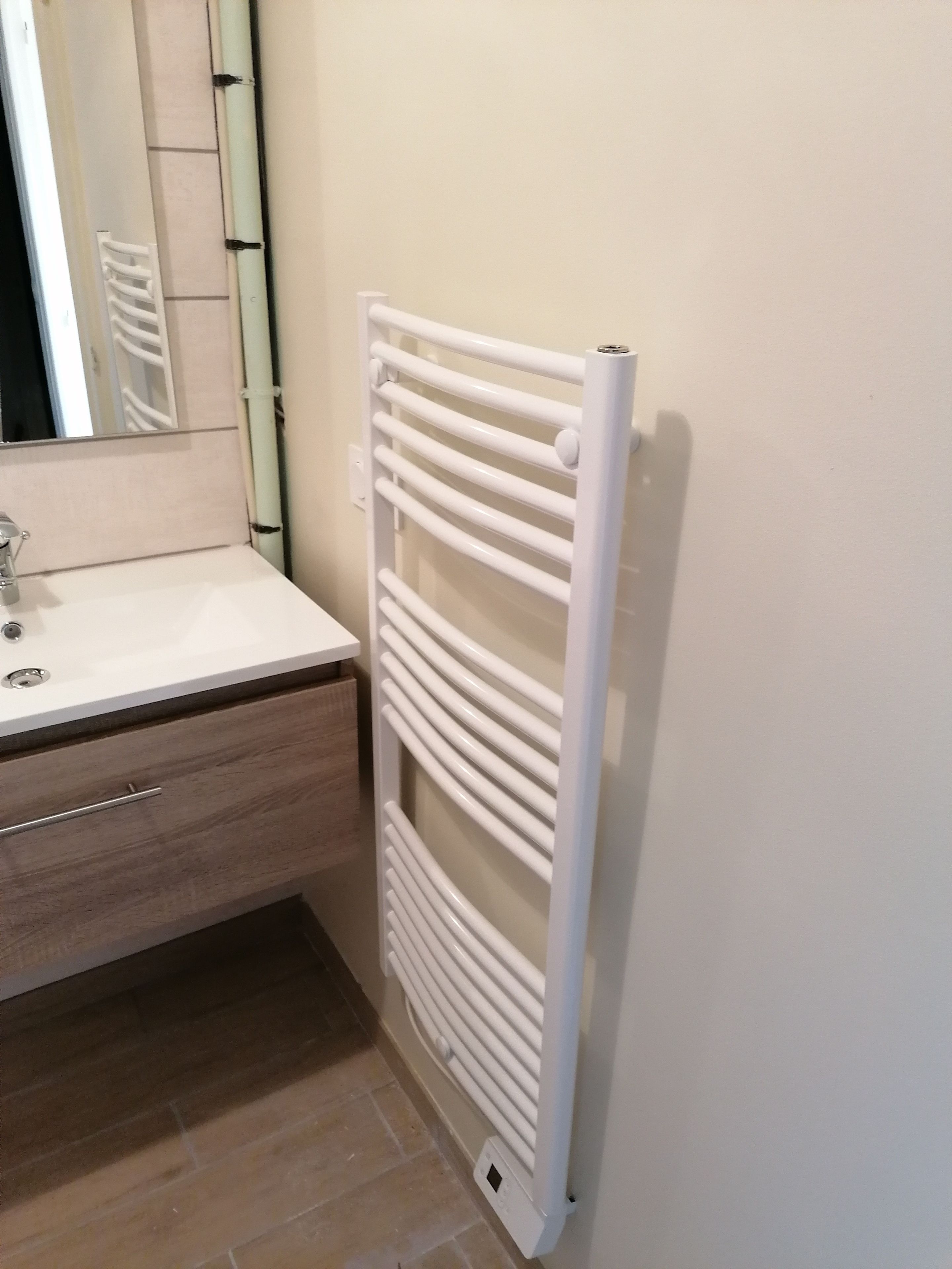 Ein Badezimmer mit einer weißen Heizung, einem Waschbecken mit Spiegel und einem Holzkorpus.