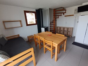 A compact living space with a bed, a dining table, and a built-in wardrobe.